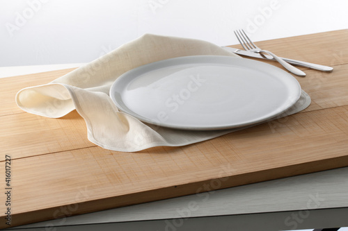 Loza blanca, plato y cubiertos sobre madera. White crockery, plate and cutlery on wood. photo