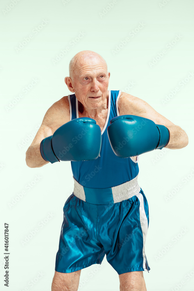 Senior man wearing sportwear boxing isolated on sky background. Caucasian male model in great shape stays active and sportive. Concept of sport, activity, movement, wellbeing. Copyspace, ad. Senior man wearing sportwear boxing isolated on sky background. Caucasian male model in great shape stays active and sportive. Concept of sport, activity, movement, wellbeing. Copyspace, ad.
