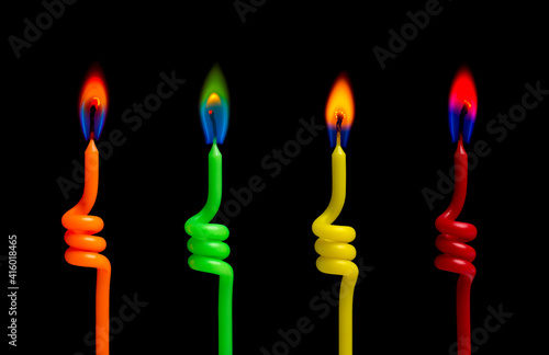 Four colorful burning candles light on the black background © fotoyou