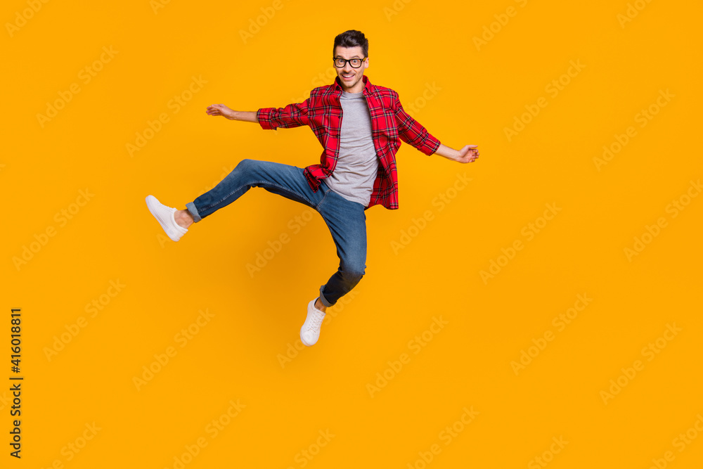 Full length photo of funny young guy dressed plaid shirt eyeglasses jumping high isolated yellow color background