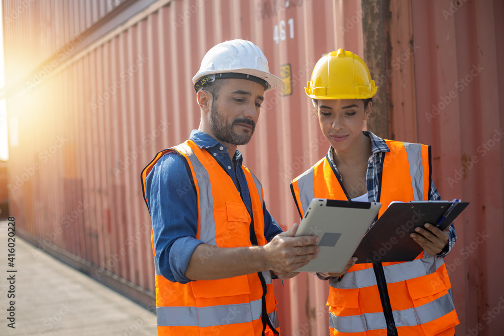 Business Logistics concept, Foreman control loading Containers box of cargo freight ship for Logistic planning and explain work with young worker woman Business Logistics concept, Foreman control loading Containers box of cargo freight ship for Logistic planning and explain work with young worker woman