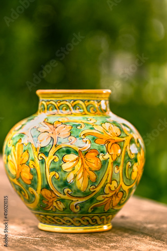 Antique colorful pot on a rustic wooden table in garden