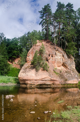 Summer landscape of red stone cliff of Zvartes rock (Zvārtes iezis) in the basin of Amata river, Latvia photo