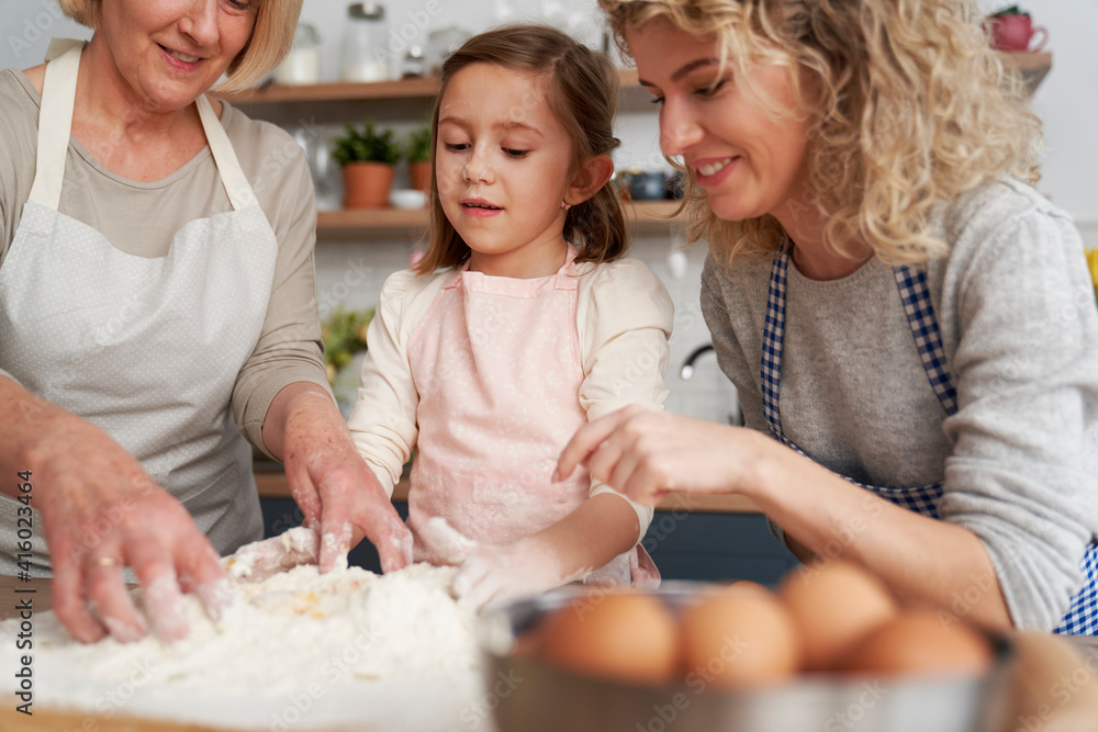 Little girl with her mom and grandma kneading dough together Little girl with her mom and grandma kneading dough together