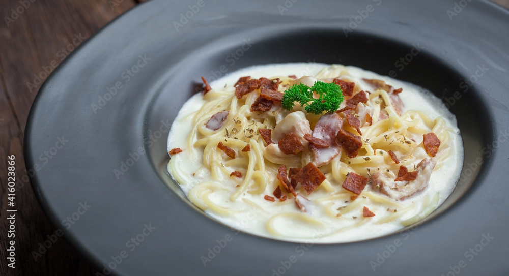 Spaghetti Carbonara White Sauce Top with Crispy Bacon and Parsley on a Black Plate Spaghetti Carbonara White Sauce Top with Crispy Bacon and Parsley on a Black Plate