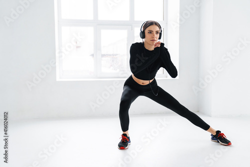 Athletic young sportswoman in headphones working out indoors