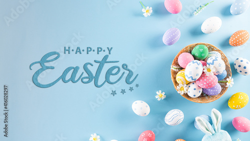 Happy easter! Colourful of Easter eggs in the nest with rabbit on pastel blue background. Greetings and presents for Easter Day celebrate time. Flat lay ,top view. © Siam