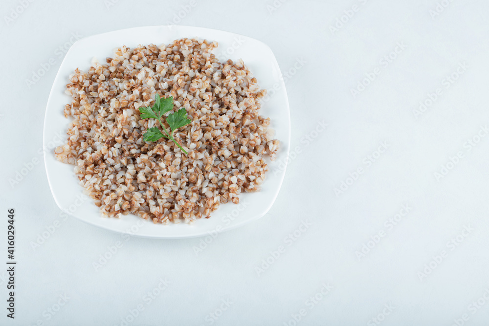 Delicious buckwheat with greens on a white plate Delicious buckwheat with greens on a white plate