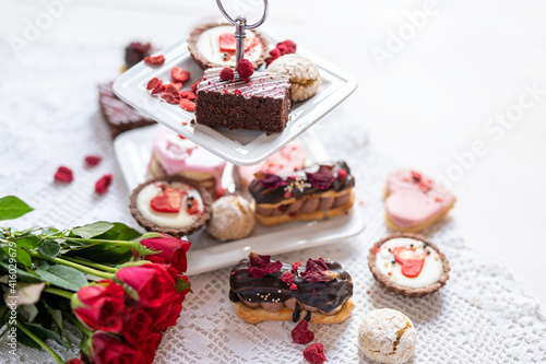 beautiful tasty romantic selection of pink chocolate love heart shape cakes for wedding, mothers day, valentines day, spring flower biscuits tartlet and rose petals 