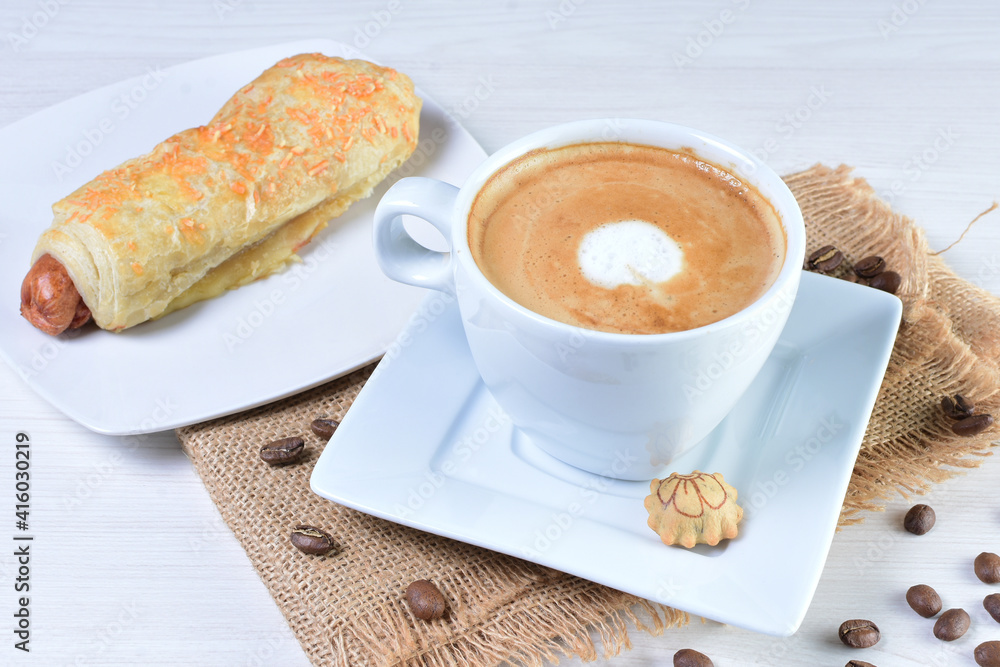 Cup of Colombian coffee, accompanied by baked bakery on white wooden background Cup of Colombian coffee, accompanied by baked bakery on white wooden background