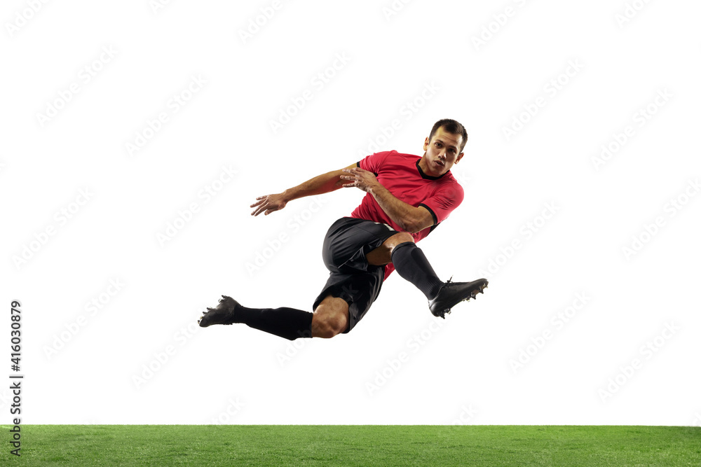 Powerful, flying above the field. Young football, soccer player in action, motion isolated on white background with green grass. Concept of sport, movement, energy and dynamic, healthy lifestyle.