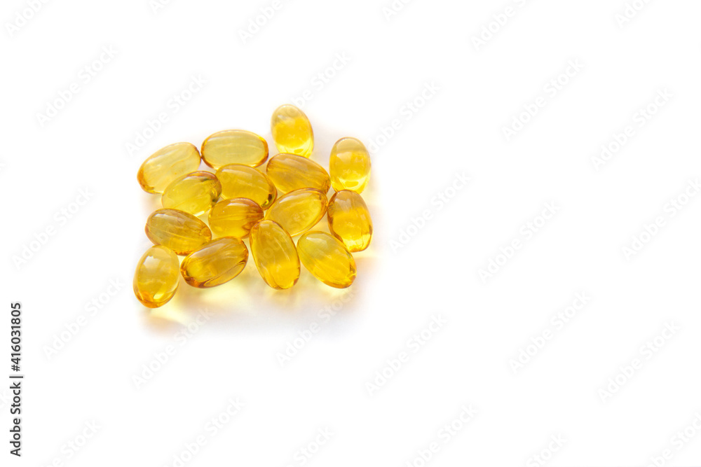 Shiny yellow fish oil capsules isolated on a white background. Vitamin E. Copy space for your text Shiny yellow fish oil capsules isolated on a white background. Vitamin E. Copy space for your text