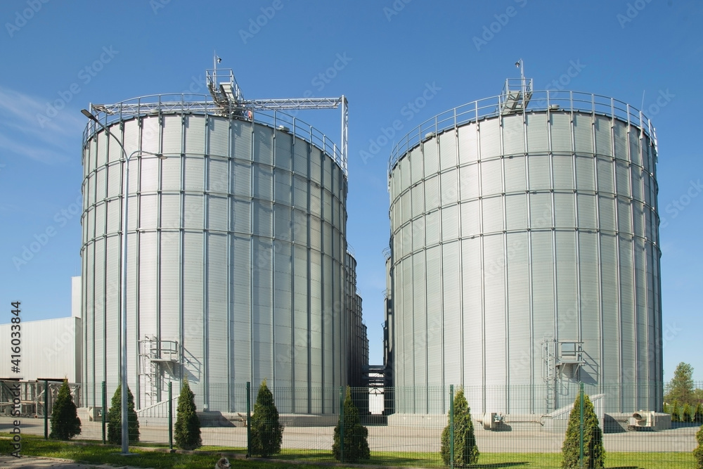 Modern granary. background A large agro-processing plant for the storage and processing of grain crops. Large metal barrels of grain. Granary elevator. Vertical image.