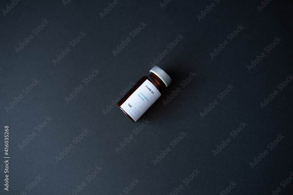 Naklejka premium A coronavirus vaccine dose vial, with a silver cap, on a black background. Health and epidemic control concept