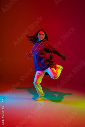 Freedom. Stylish sportive girl dancing hip-hop in stylish clothes on colorful background at dance hall in neon light. Youth culture  movement  style and fashion  action. Fashionable bright portrait.