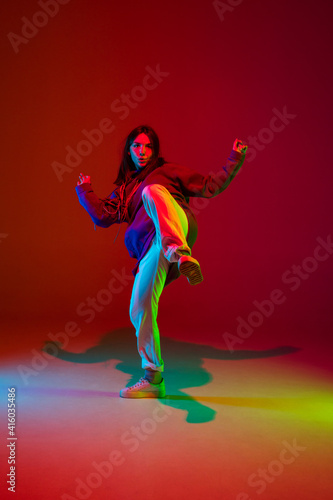Freedom. Stylish sportive girl dancing hip-hop in stylish clothes on colorful background at dance hall in neon light. Youth culture, movement, style and fashion, action. Fashionable bright portrait. © master1305