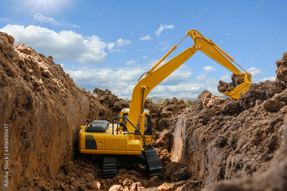 Yellow excavators are digging the soil in the construction site with the sky and sunbeam background Yellow excavators are digging the soil in the construction site with the sky and sunbeam background