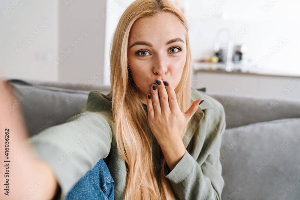 Happy blonde woman blowing air kiss while taking selfie photo Happy blonde woman blowing air kiss while taking selfie photo
