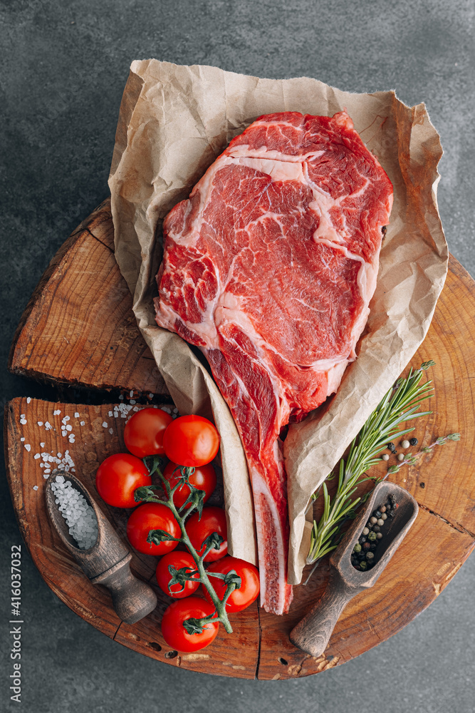 fresh raw cowboy tomahawk steak on a round wooden cutting board for meat