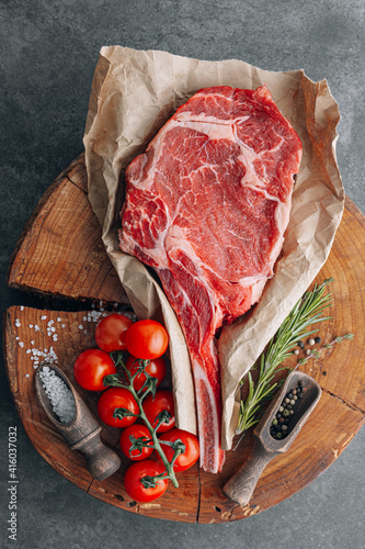 fresh raw cowboy tomahawk steak on a round wooden cutting board for meat