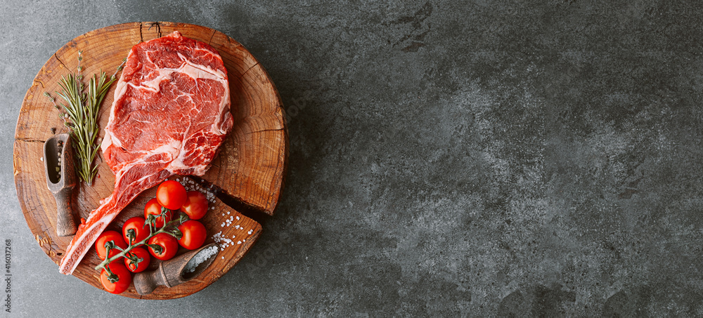 fresh raw cowboy tomahawk steak on a round wooden cutting board for meat