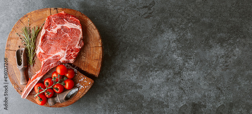 Obraz na płótnie fresh raw cowboy tomahawk steak on a round wooden cutting board for meat w salonie