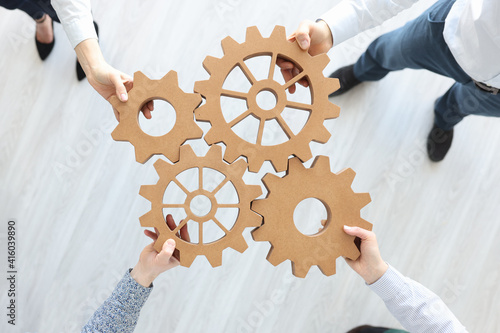 Group of business people stacking wooden gears top view photo