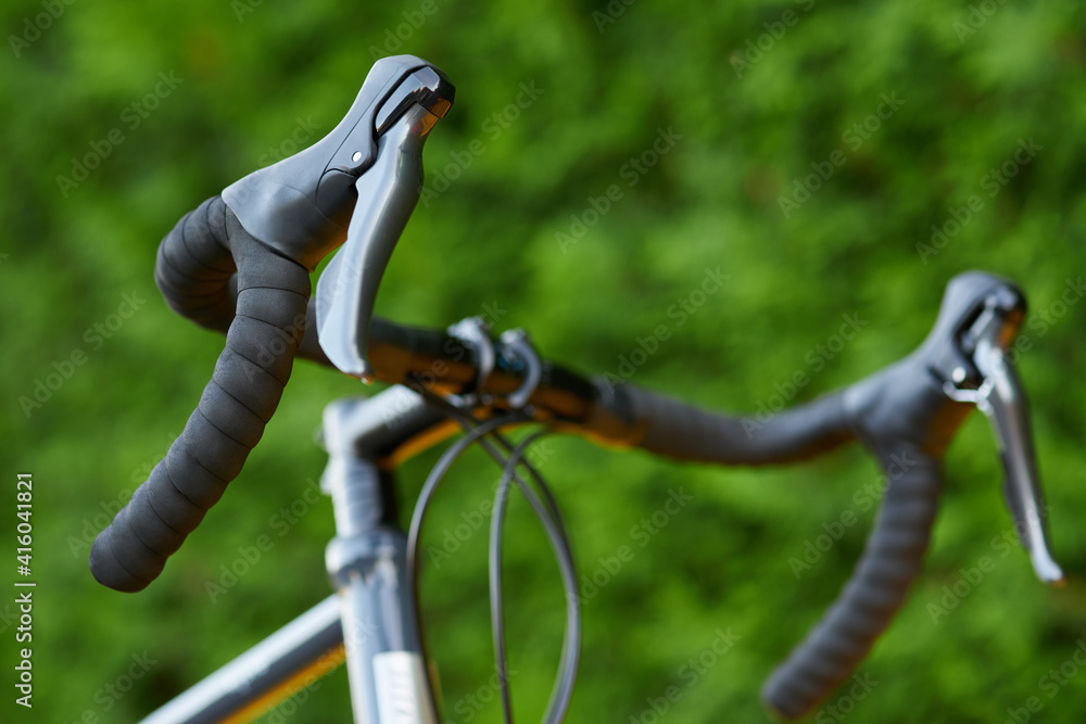 Fototapeta premium Details. Close up shot of handlebar of road bicycle on green nature background