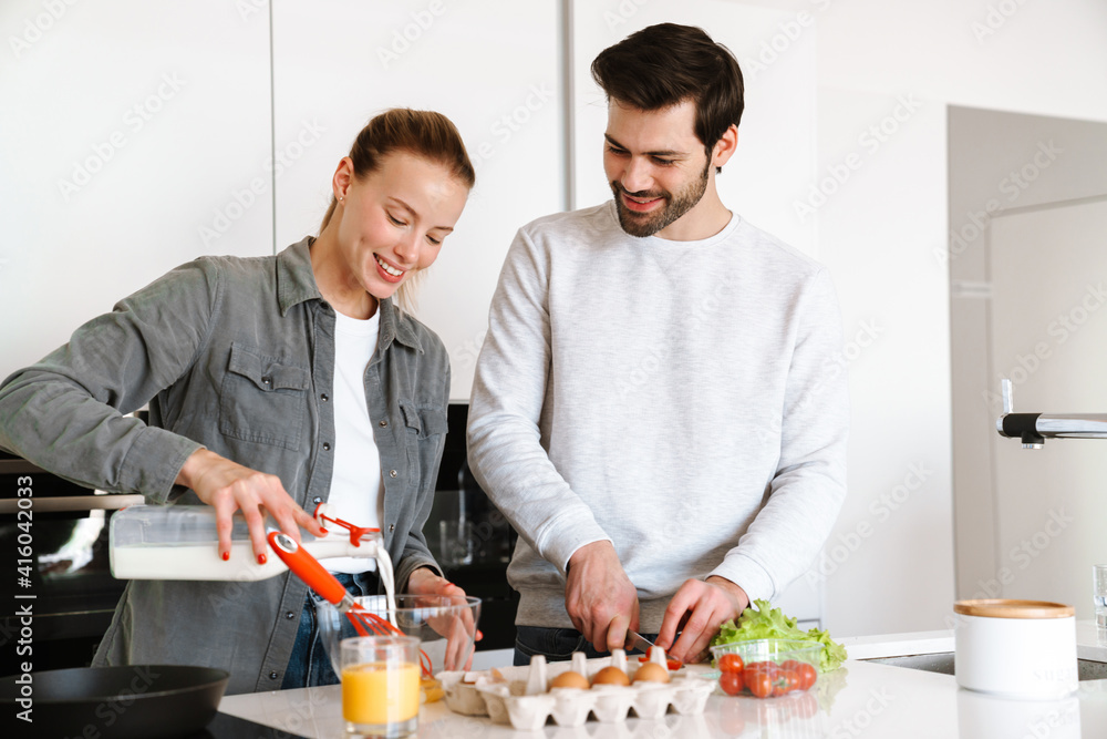 Attractive young couple cooking breakfast at the kitchen Attractive young couple cooking breakfast at the kitchen