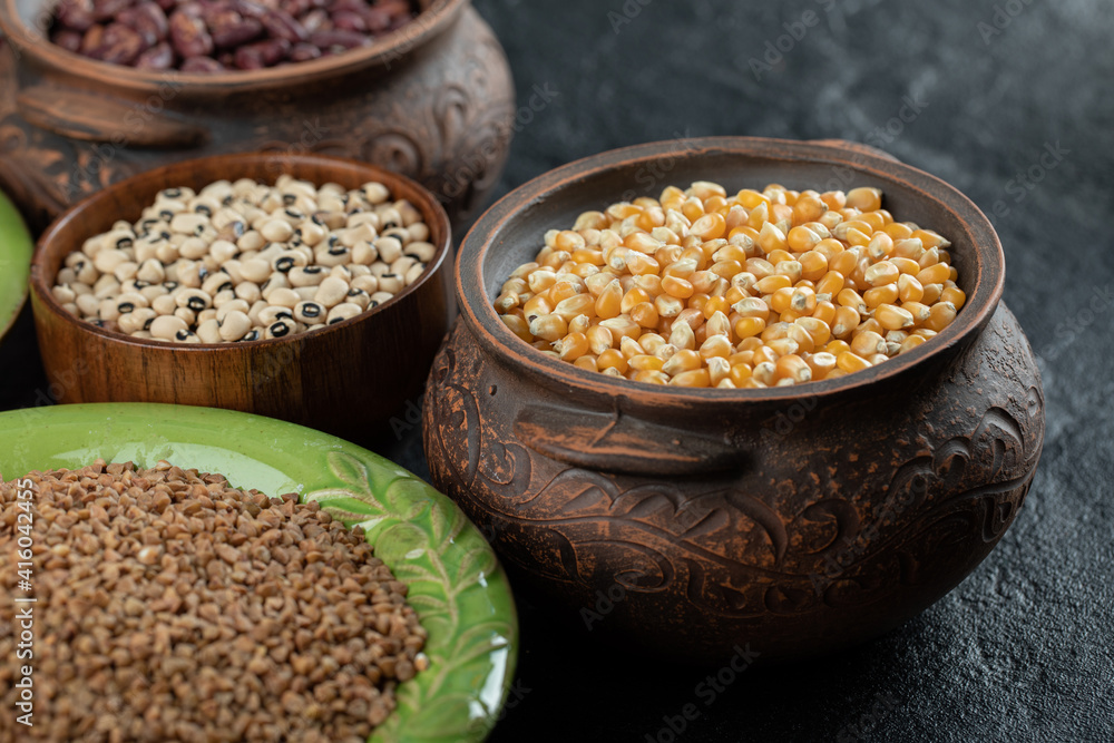 Different kinds of bean seeds, lentil, peas in dishes on a dark background Different kinds of bean seeds, lentil, peas in dishes on a dark background