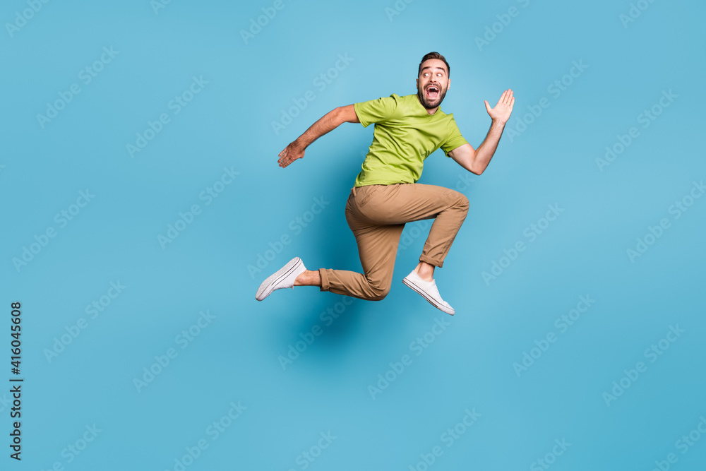 Full length profile side photo of young man jump up run empty space look back isolated on pastel blue color background