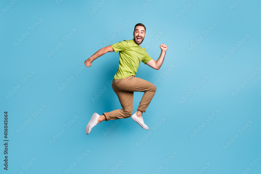 Full body profile side photo of crazy funky positive man jump up run empty space isolated on blue color background