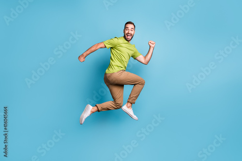 Full body profile side photo of crazy funky positive man jump up run empty space isolated on blue color background