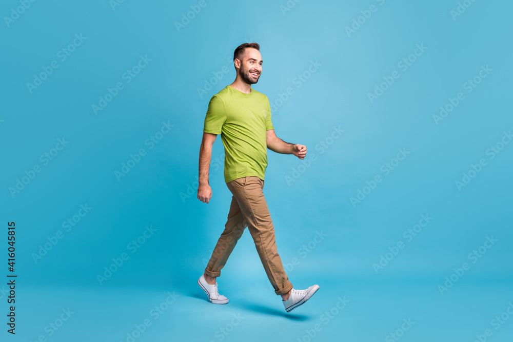 Full length profile side photo of happy young man walk empty space weekend travel isolated on blue color background