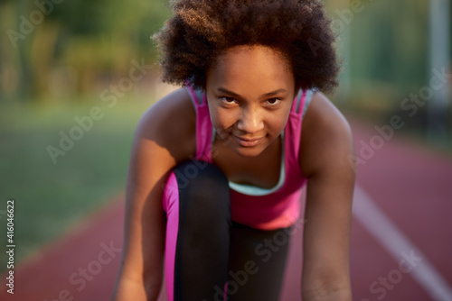 Cute girl runner standing in start position before the sprint