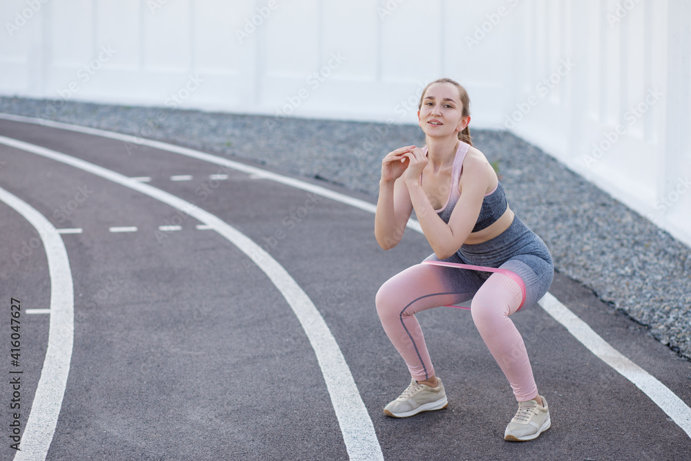 Young sportive woman doing exercises with elastic band outdoor Young sportive woman doing exercises with elastic band outdoor