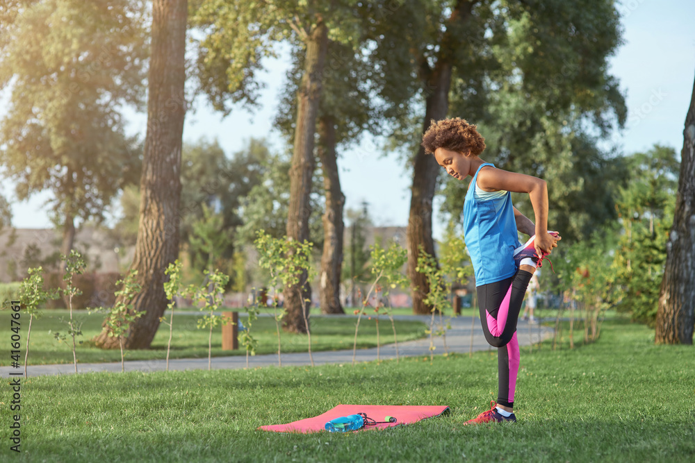 Cute Afro American girl stretching legs in park Cute Afro American girl stretching legs in park