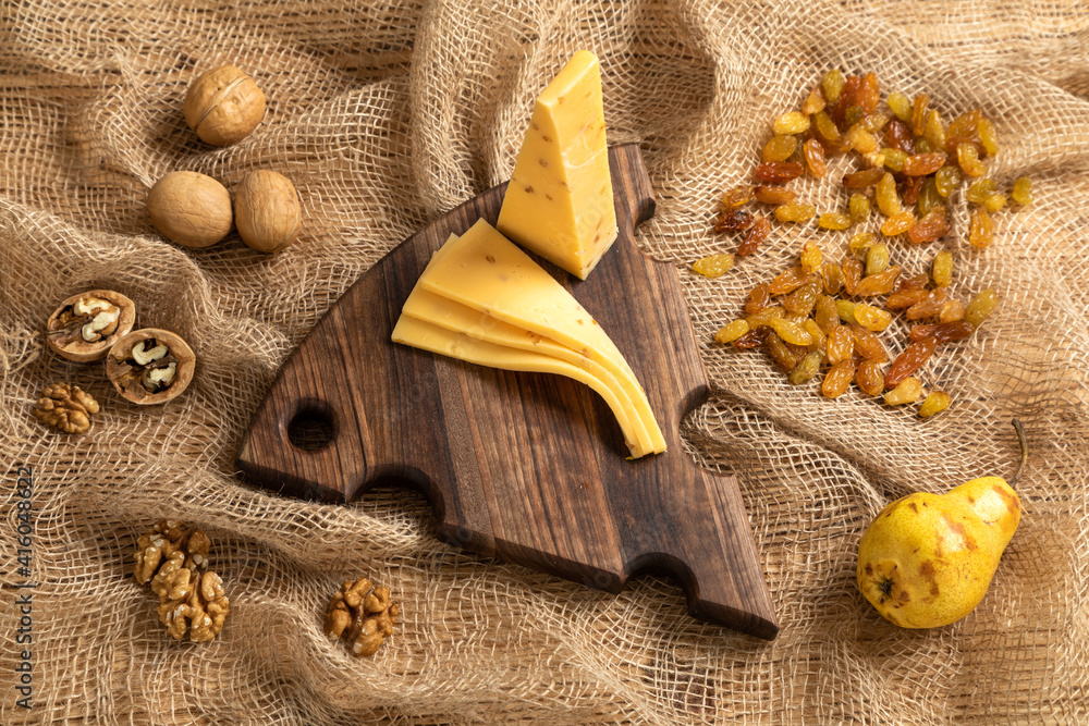 Cheese, pears and nuts on a wooden cutting board