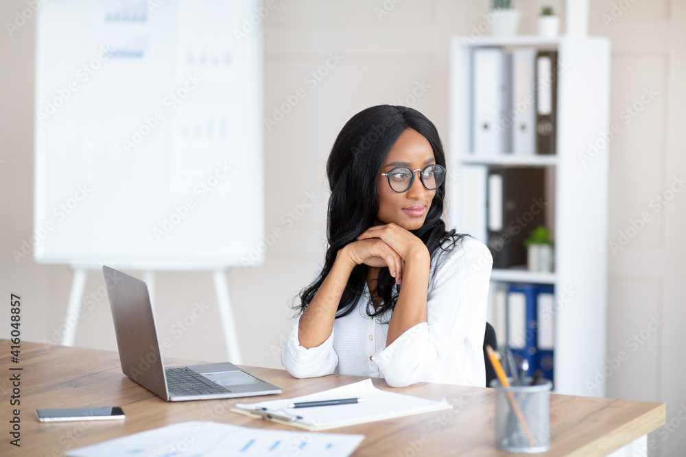 Portrait of young female secretary daydreaming in front of laptop at workplace, copy space Portrait of young female secretary daydreaming in front of laptop at workplace, copy space