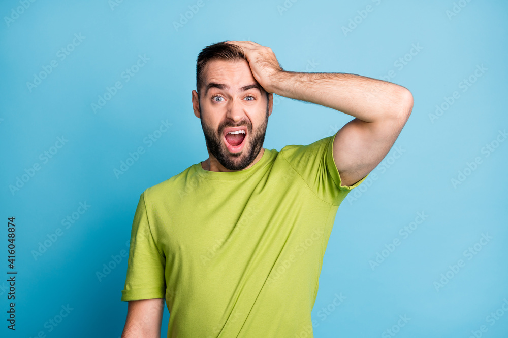 Photo of unhappy man hold hand head suffer pain wear green t-shirt isolated on pastel blue color background Photo of unhappy man hold hand head suffer pain wear green t-shirt isolated on pastel blue color background