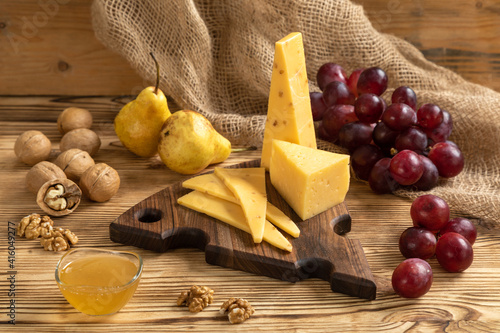 Obraz na płótnie Cheese, grapes and nuts on a cutting board w salonie