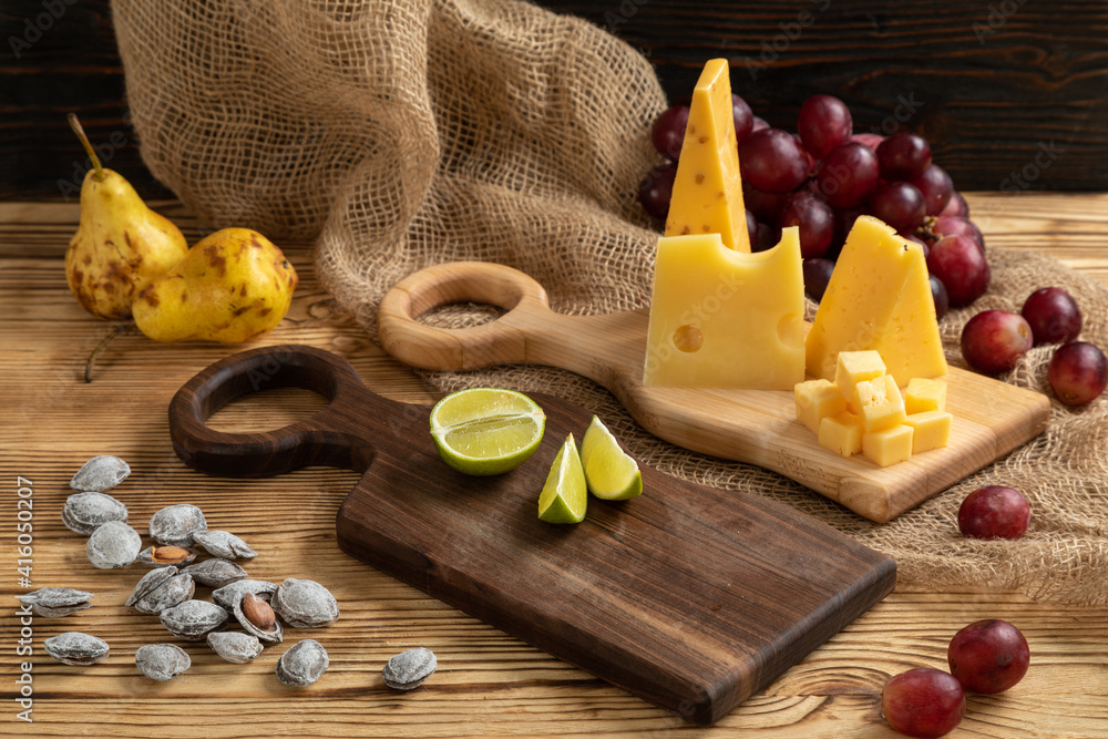Cheese, grapes, lime, pear and nuts on a cutting board
