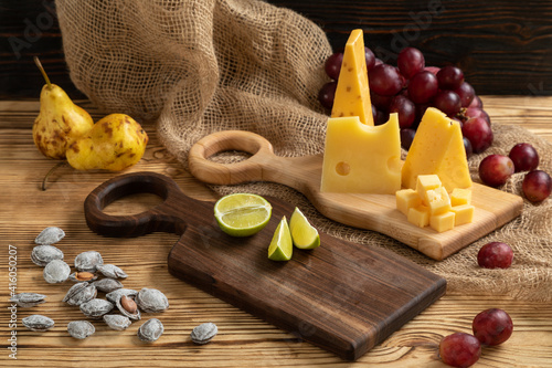 Obraz na płótnie Cheese, grapes, lime, pear and nuts on a cutting board w salonie