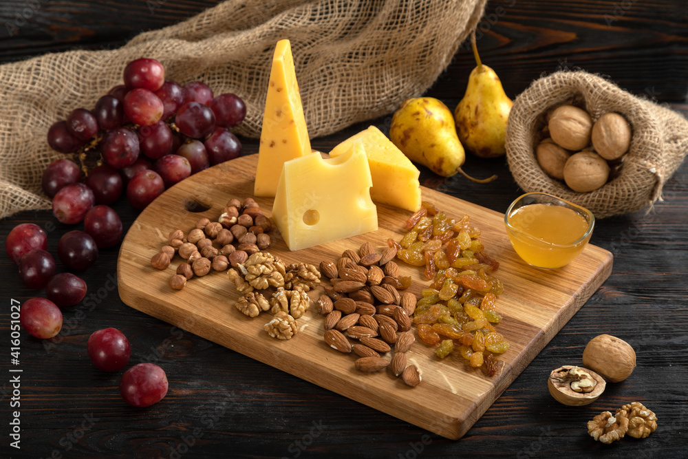 Cheese, grapes and nuts on a cutting board