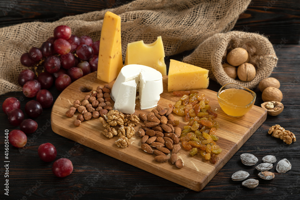 Cheese, grapes and nuts on a cutting board