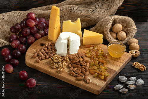 Obraz na płótnie Cheese, grapes and nuts on a cutting board w salonie