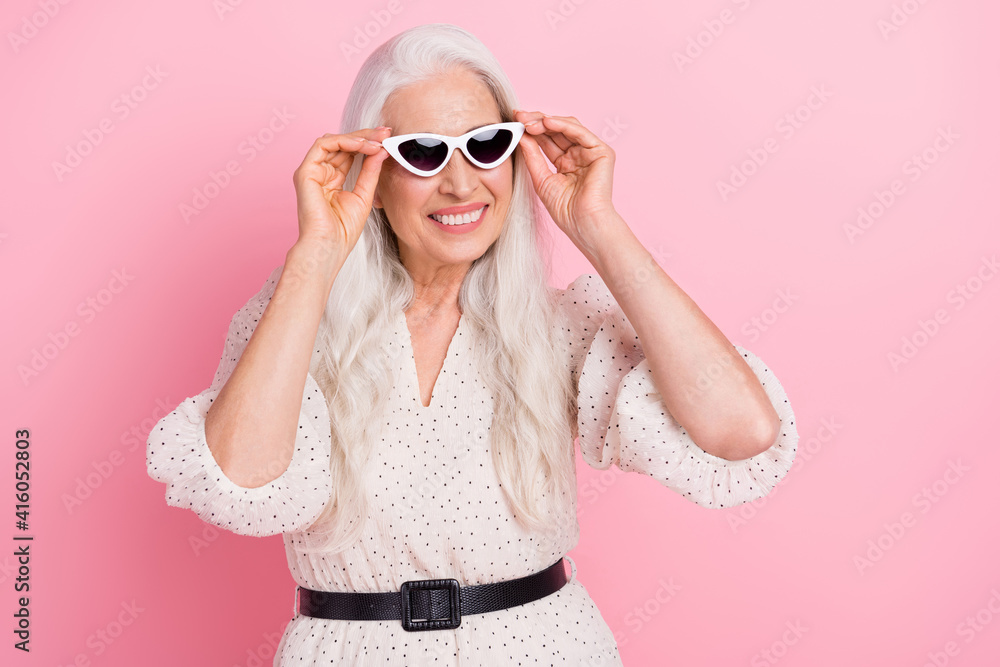 Portrait of attractive cheerful dreamy grey-haired woman touching specs adventure isolated over pink pastel color background Portrait of attractive cheerful dreamy grey-haired woman touching specs adventure isolated over pink pastel color background
