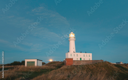 The moon sets over the lighthouse at dawn, Flamborough, Yorkshire, UK.