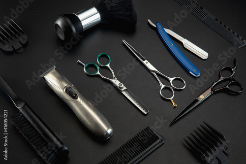Barber shop equipment set isolated on black table background. Close up sccissors, comb, brushes, razors, professional tools of hairdresser. Professional occupation, art, self-care concept. Magazine.