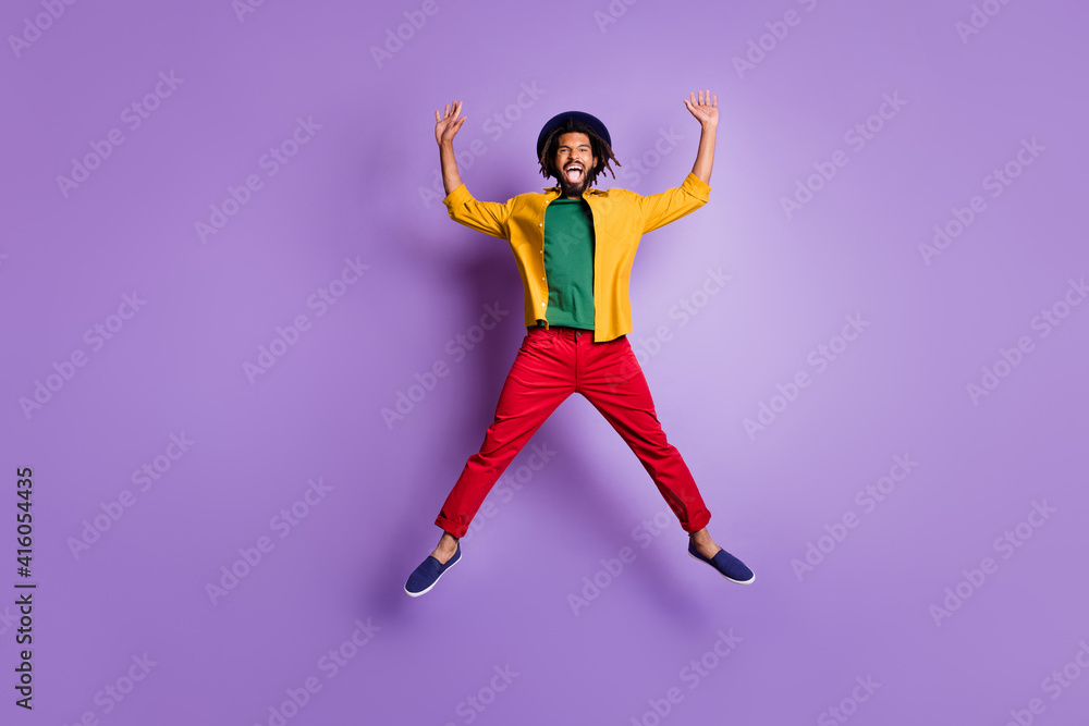 Full length photo of cheerful dark skin guy dressed yellow shirt jumping high rising arms hands isolated purple color background